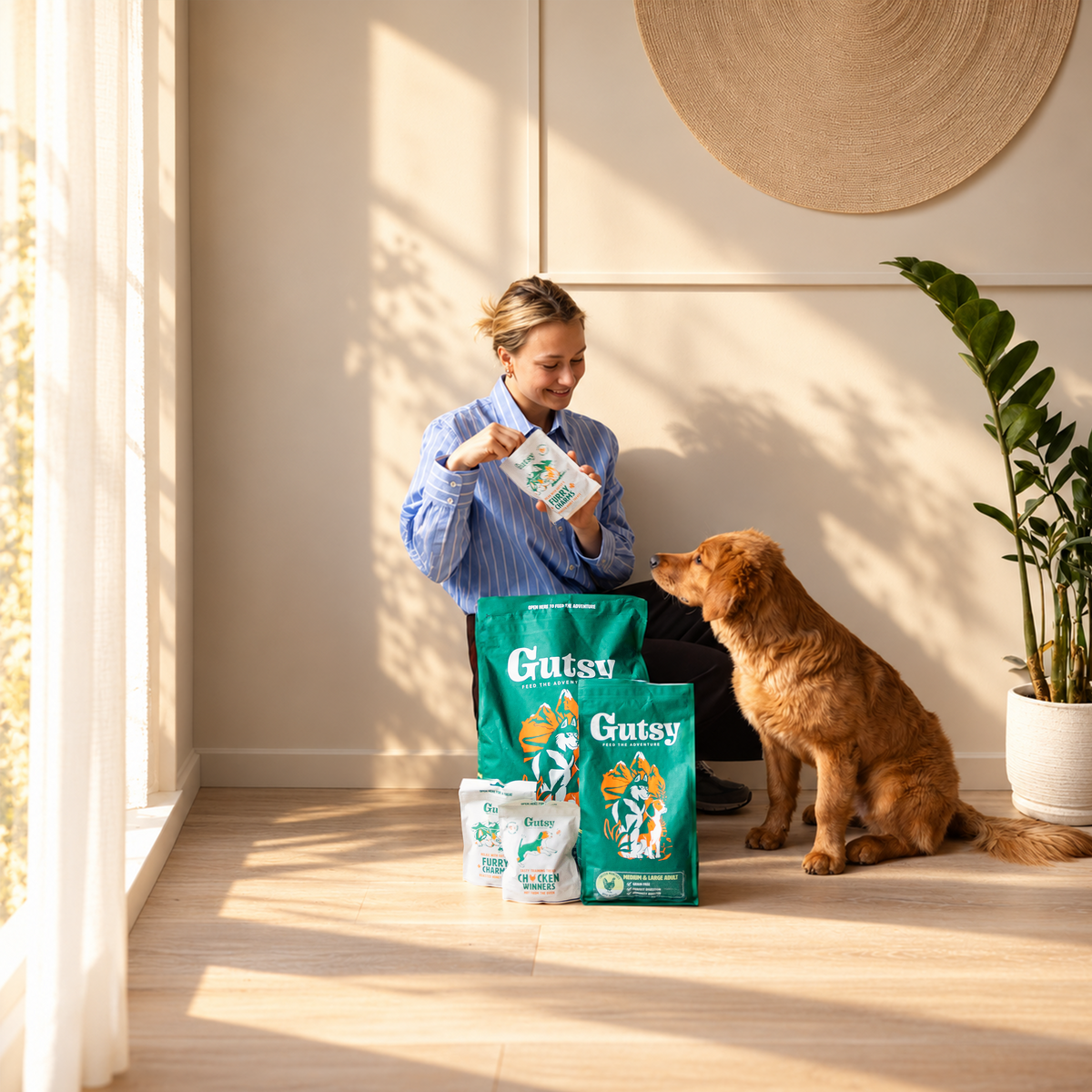 Vrouw geeft haar hond Gutsy hondenvoer, met zakken Gutsy droogvoer op de vloer